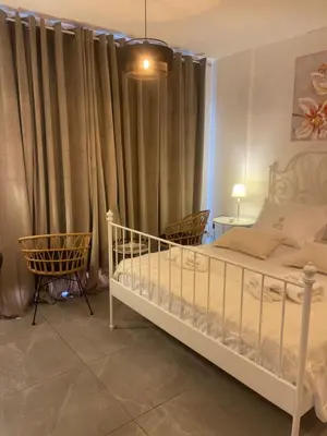 a bedroom with a bed and two chairs and curtains at Lazuli Sea View & Pool Studio 303 in Larnaka