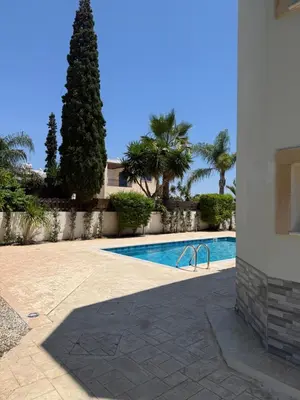 a swimming pool next to a building with palm trees at Villa Porta Aurea in Ayia Napa