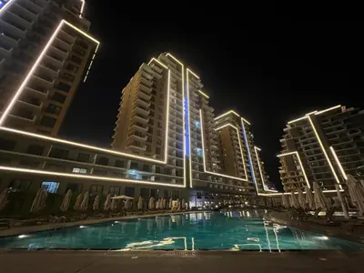 a pool in front of some tall buildings at night at Riverside Life Residence in İskele