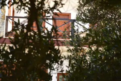 a building with a balcony with trees in the foreground at Ecolive Guest House in Ayios Epiphanios