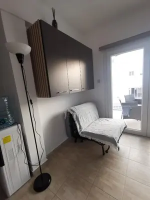 a living room with a chair and a floor lamp at Kennedy 5 apartman Ayia Napa in Ayia Napa