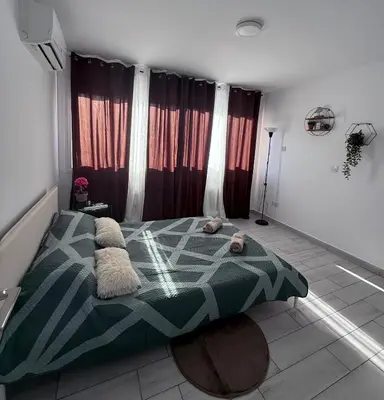 a bedroom with a bed in a room with curtains at Kypa rooms 50 steps to the beach in Larnaka