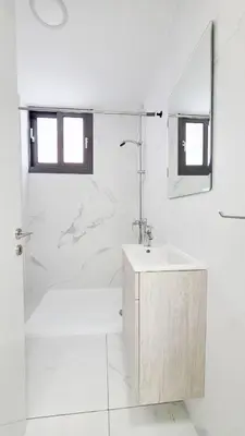 a white bathroom with a sink and a shower at Poolside Lux Apartment in Larnaka