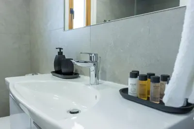 a bathroom sink with a mirror and some products on it at Stylish Modern City Center Stay in Nicosia