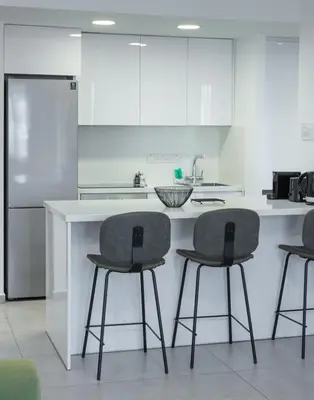a kitchen with three bar stools in front of a counter at Stylish Modern City Center Stay in Nicosia