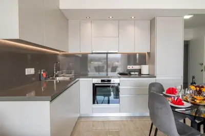 a kitchen with white cabinets and a table with chairs at AURA Apt Modern 1BR in Central Limassol and Free Parking in Limassol