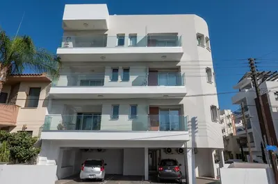 a white building with cars parked in front of it at AURA Apt Modern 1BR in Central Limassol and Free Parking in Limassol