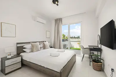 a white bedroom with a large bed and a desk at Chic & Elegant Hideaway - Your Luxury Escape in Livadhia