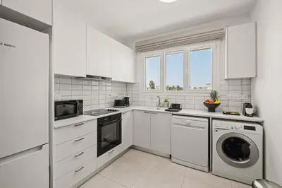 a kitchen with white cabinets and a washer and dryer at Chic & Elegant Hideaway - Your Luxury Escape in Livadhia