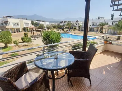 a balcony with a glass table and chairs and a pool at Esentepe Turtle Bay Village - The Boho Breeze Holiday Home in Aglantzia