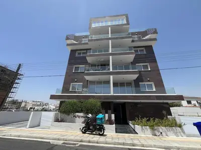 a motorcycle parked in front of a tall building at One Bedroom Penthouse Flat in Larnaka