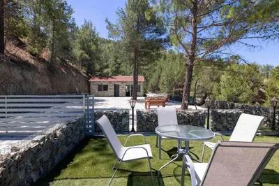 a patio with chairs and a table and a fence at Palaiomylos Forest Residence