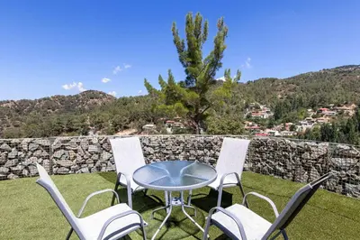 a patio with a table and chairs and a stone wall at Palaiomylos Forest Residence