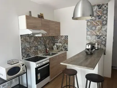 a kitchen with a sink and a counter with stools at Panos salt lake apartment in Aglantzia