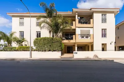 a large white building with palm trees and a street at 2BR Apartment with Amazing View and Pool in Kiti in Kiti