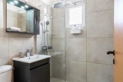a bathroom with a shower and a sink and a mirror at Stylish 2BR Apartment with Rooftop Pool in Mackenzie in Larnaka