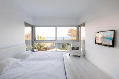 a white bedroom with a large bed and a chair at Katerina House in Pervolia