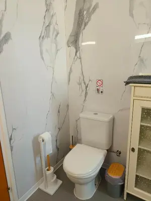 a bathroom with a white toilet and marble walls at Possidon Beach Getaway in Meneou