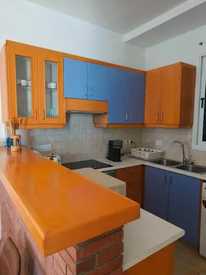a kitchen with blue cabinets and a wooden counter top at Possidon Beach Getaway in Meneou