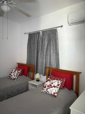 a bedroom with two beds with red pillows and a window at Ikaria Village, Maisonette Sea 10 in Aglantzia