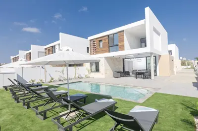 a villa with a swimming pool with chairs and an umbrella at Orea Luxury Villas in Ayia Napa