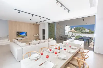 a dining room with white furniture and a table and chairs at Orea Luxury Villas in Ayia Napa