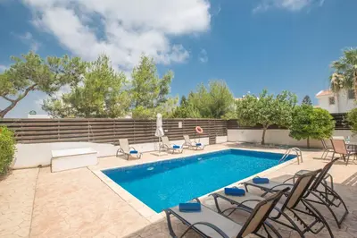 a swimming pool with chairs next to a fence at Mandali Villa in Protaras