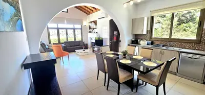 a kitchen and living room with a table and chairs at Agia Thekla bungalow with pool in Ayia Napa