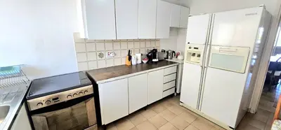 a kitchen with white cabinets and a stove and refrigerator at Retro art and mirrors Molos in Limassol