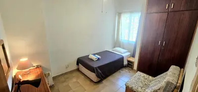 a small bedroom with a bed and a chair at Retro art and mirrors Molos in Limassol