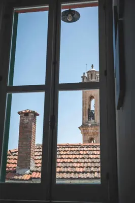 a window view of a clock tower from a building at Elite luxury Suites in Omodos
