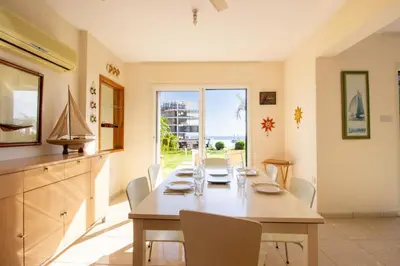 a dining room with a table and chairs and a window at Frontline Sea-View Villa in Paralimni