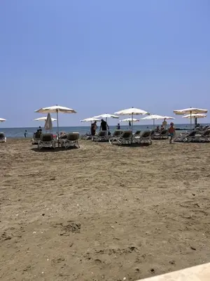 a beach with chairs and umbrellas on the sand at Sandy Nest Studio in Larnaka