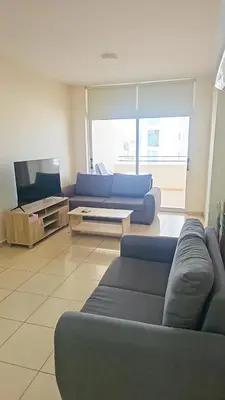 a living room with a blue couch and a tv at The Poolside Escape Apartment in Larnaka