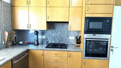 a kitchen with wooden cabinets and a stove top oven at Modern 3BDR_Top Floor_Lux_Suite_Balcony in Limassol