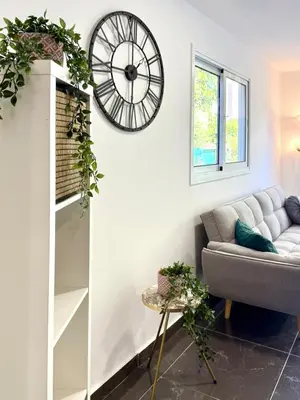 a living room with a couch and a clock on the wall at Elegant Beach Villa Moonstone II in Meneou