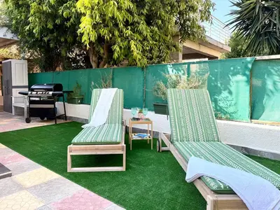two lounge chairs and a table on a green rug at Elegant Beach Villa Moonstone II in Meneou