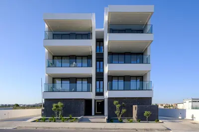 a white apartment building with trees in front of it at Artemis 105 - Seaside Stories in Livadhia