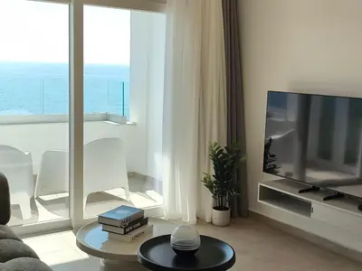 a living room with a television and a large window at Joyscape beachfront residence in Larnaka