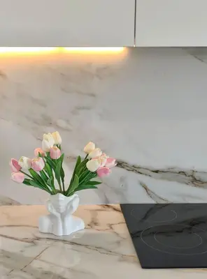 a white vase with pink flowers on a table at Joyscape beachfront residence in Larnaka