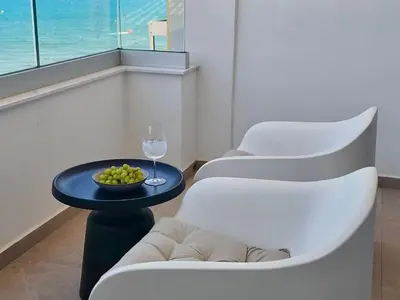 two white chairs and a table with a glass of wine at Joyscape beachfront residence in Larnaka