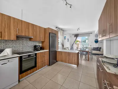a kitchen with wooden cabinets and a dining room at Villa Rena - 3BR Retreat near Kalamies Beach in Paralimni