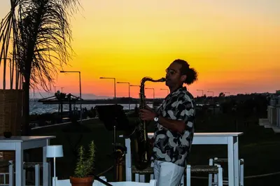 a man playing a saxophone with the sunset in the background at Piere - Anne Beach Hotel in Ayia Napa