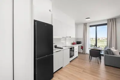 a kitchen with white cabinets and a black refrigerator at Artemis 106 - Seaside Stories in Livadhia