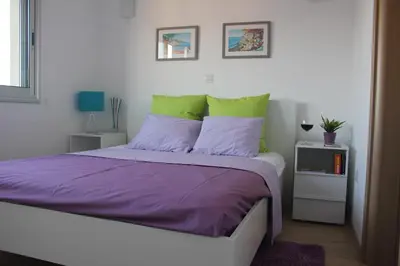 a bedroom with a bed with purple and green pillows at Eden Beach Apartment 611 in Limassol