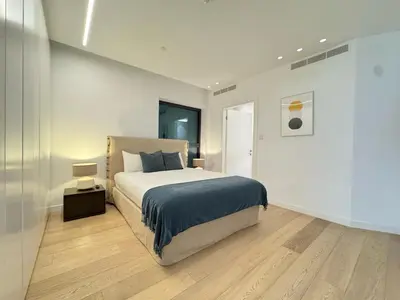 a white bedroom with a bed and a night stand at SkyHigh Park View Residence in Nicosia