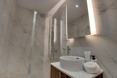 a white bathroom with a sink and a shower at Oniro Suites Makenzy in Larnaka