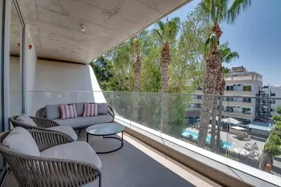 a balcony with a couch and chairs and palm trees at Oniro Suites Makenzy in Larnaka