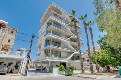 a white building with palm trees in front of it at Oniro Suites Makenzy in Larnaka
