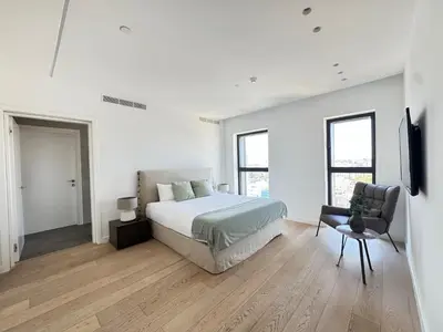 a white bedroom with a bed and a chair at SkyHigh Park View Living in Nicosia
